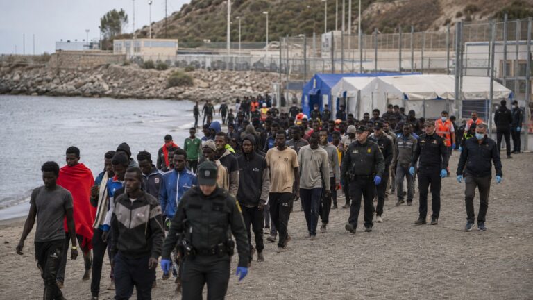 Ceuta sınır krizi sırasında kıyı hattında polis eşliğinde ilerleyen kalabalık grup.