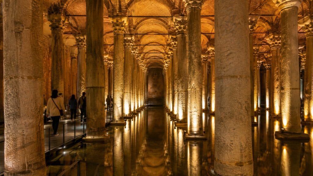 Interior de la Cisterna Basílica en Estambul con columnas iluminadas y pasarela para visitantes