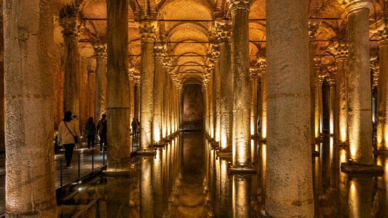 Interior de la Cisterna Basílica en Estambul con columnas iluminadas y pasarela para visitantes