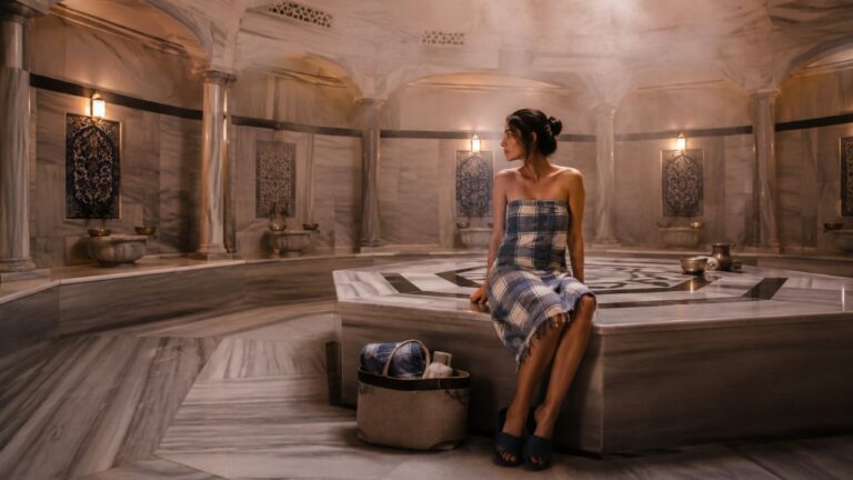 Interior de un hammam tradicional con una visitante sentada sobre la piedra central