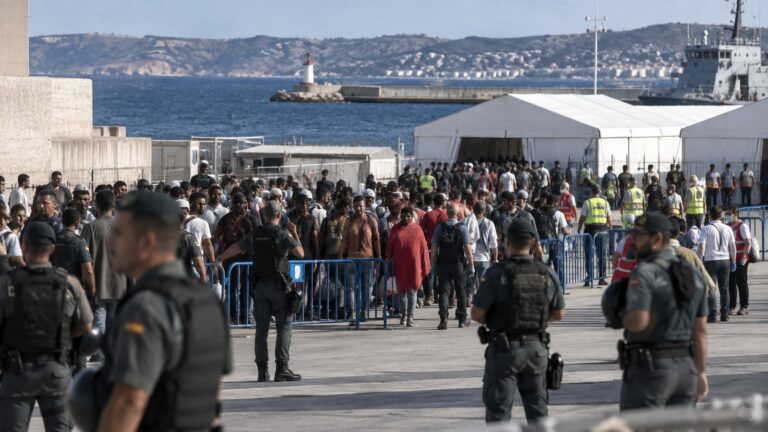 Ceuta göçmen nakli sırasında limandaki geçici tesise yönlendirilen kalabalık ve güvenlik görevlileri